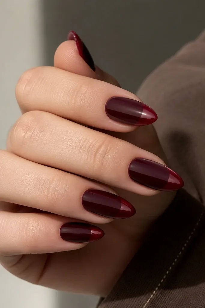 Short stiletto nails with a deep oxblood base. The free edge has a glossy, slightly lighter oxblood glaze band about 1 mm wide, with a super crisp line at the start of the tip.