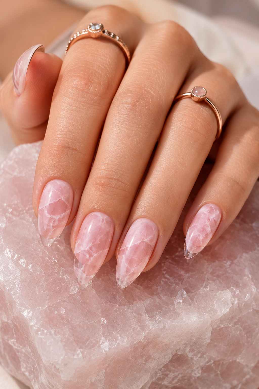 Short stiletto nails with a pale rose quartz base. Thin marble veining runs across each nail in slightly darker pink, plus a couple of clear gel vein lines that look raised. Glossy finish.