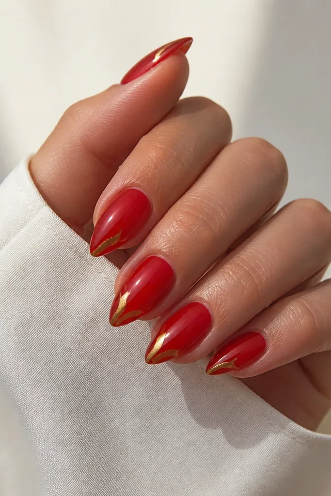 Short stiletto nails with translucent red jelly base. At the very tip there's a small gold glaze drip effect, like a thin streak that stops before the edge. Glossy and smooth.