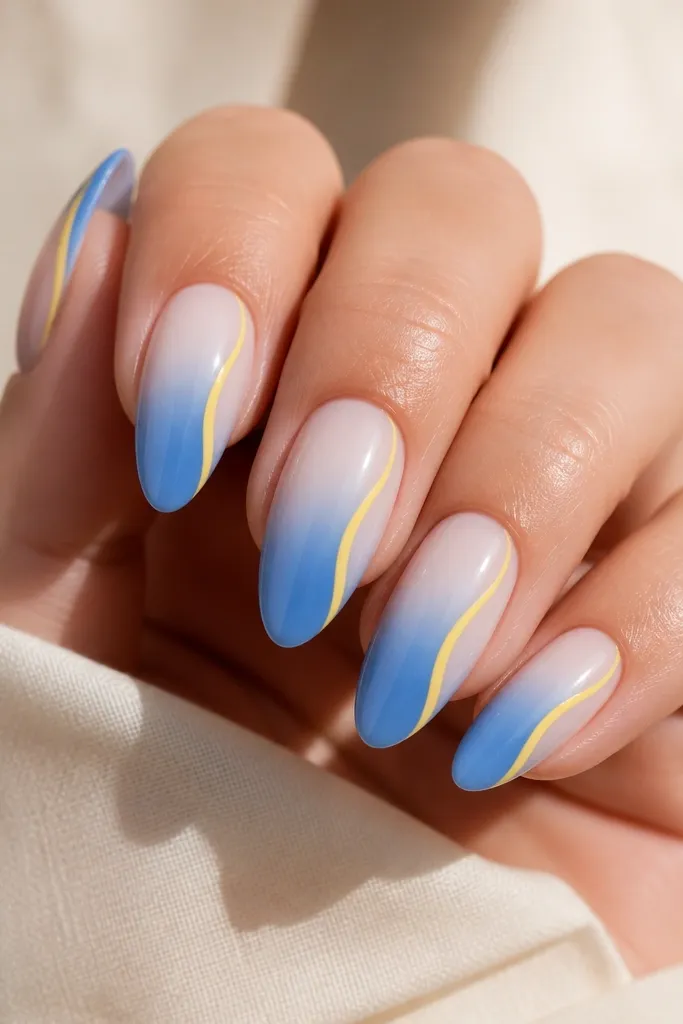Nails fade from powder blue at the tip to clear near the cuticle. Along one sidewall, there's a thin yellow line running from mid-nail to the tip. Glossy finish.