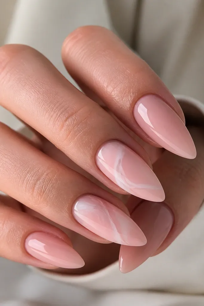 Short stiletto nails in a sheer pink base; two nails have a thin rose quartz style swirl in soft white and pale pink, all glossy.