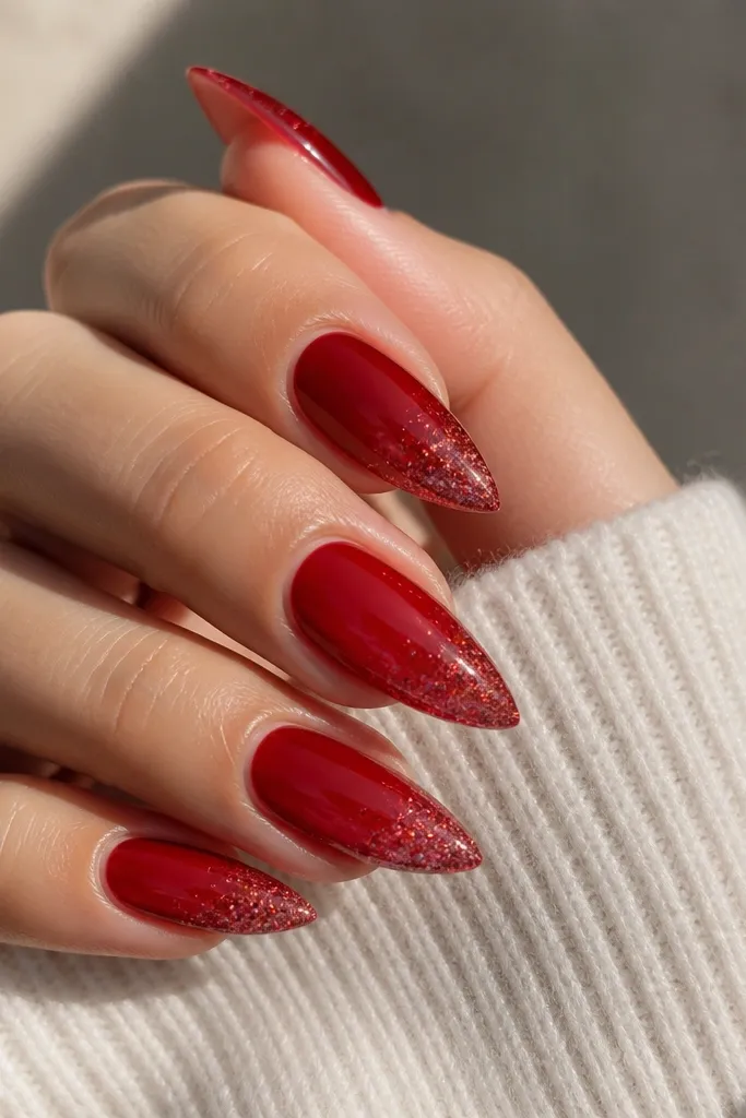 Short stiletto nails with a translucent red jelly base; micro glitter is concentrated on the tips, glossy finish.