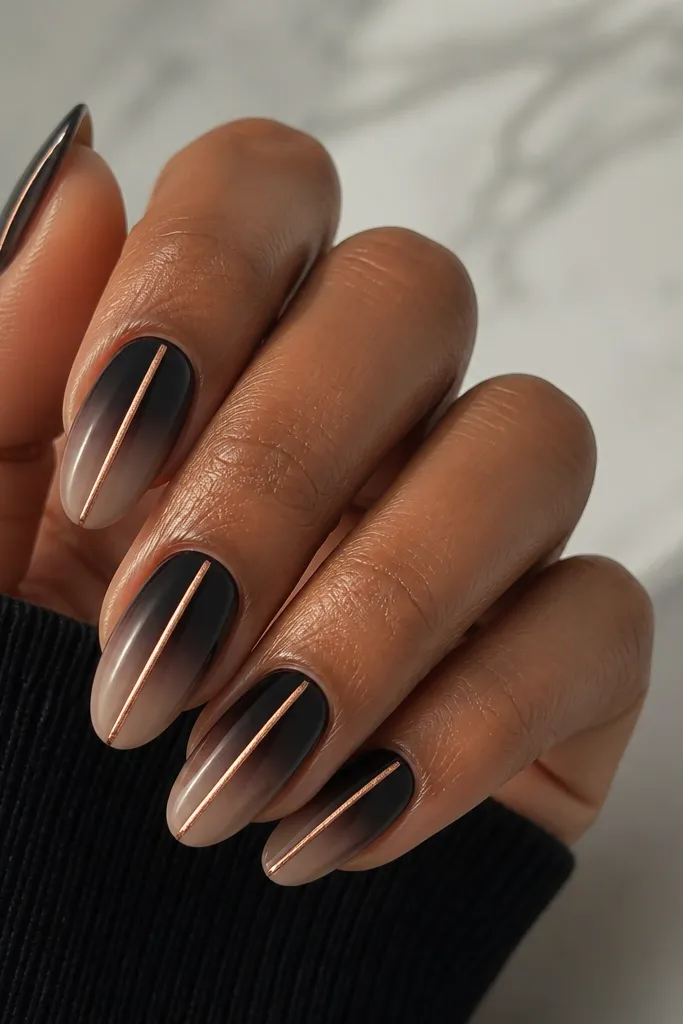 A black nude ombre fades from near-black at the cuticle into soft taupe at the tips, with a single rose gold chrome stripe running down the center of each nail.