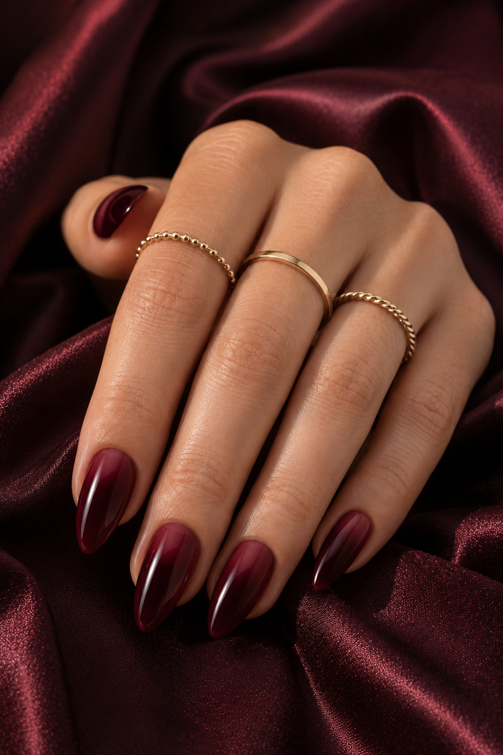 Short stiletto nails in oxblood red with a soft smoky gradient near the cuticle that fades upward; the center of each nail is darker and the top stays glossy.