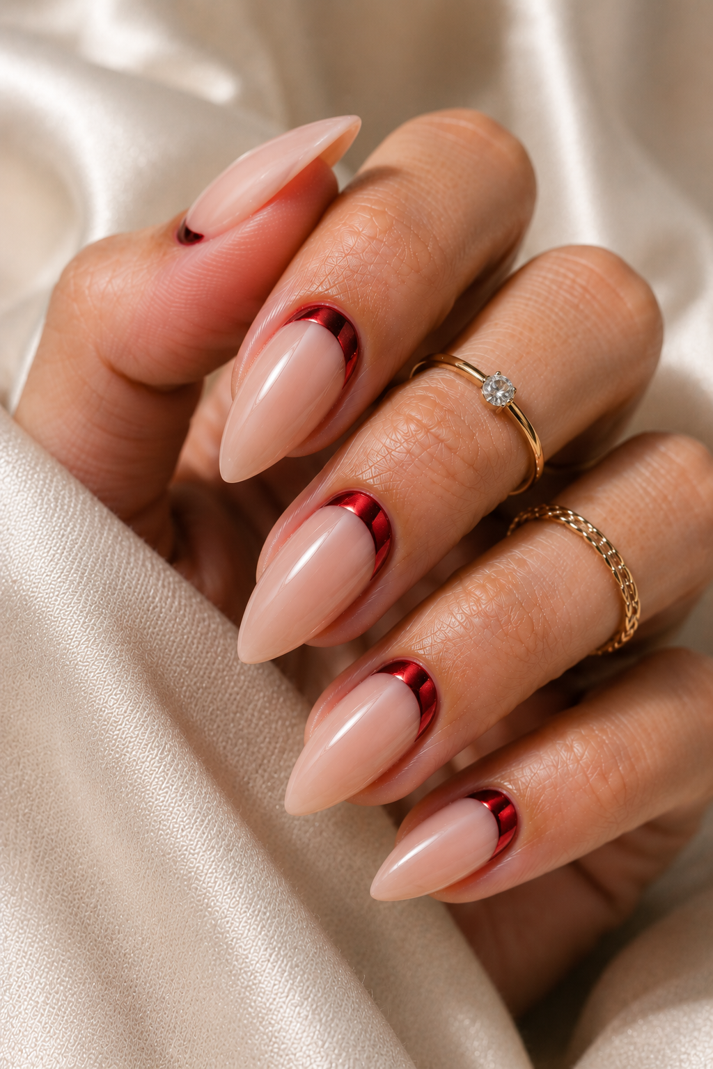 Nude short stiletto nails with a red chrome half-moon at the cuticle; the chrome looks metallic and reflective, and the rest of the nail is sheer glossy.