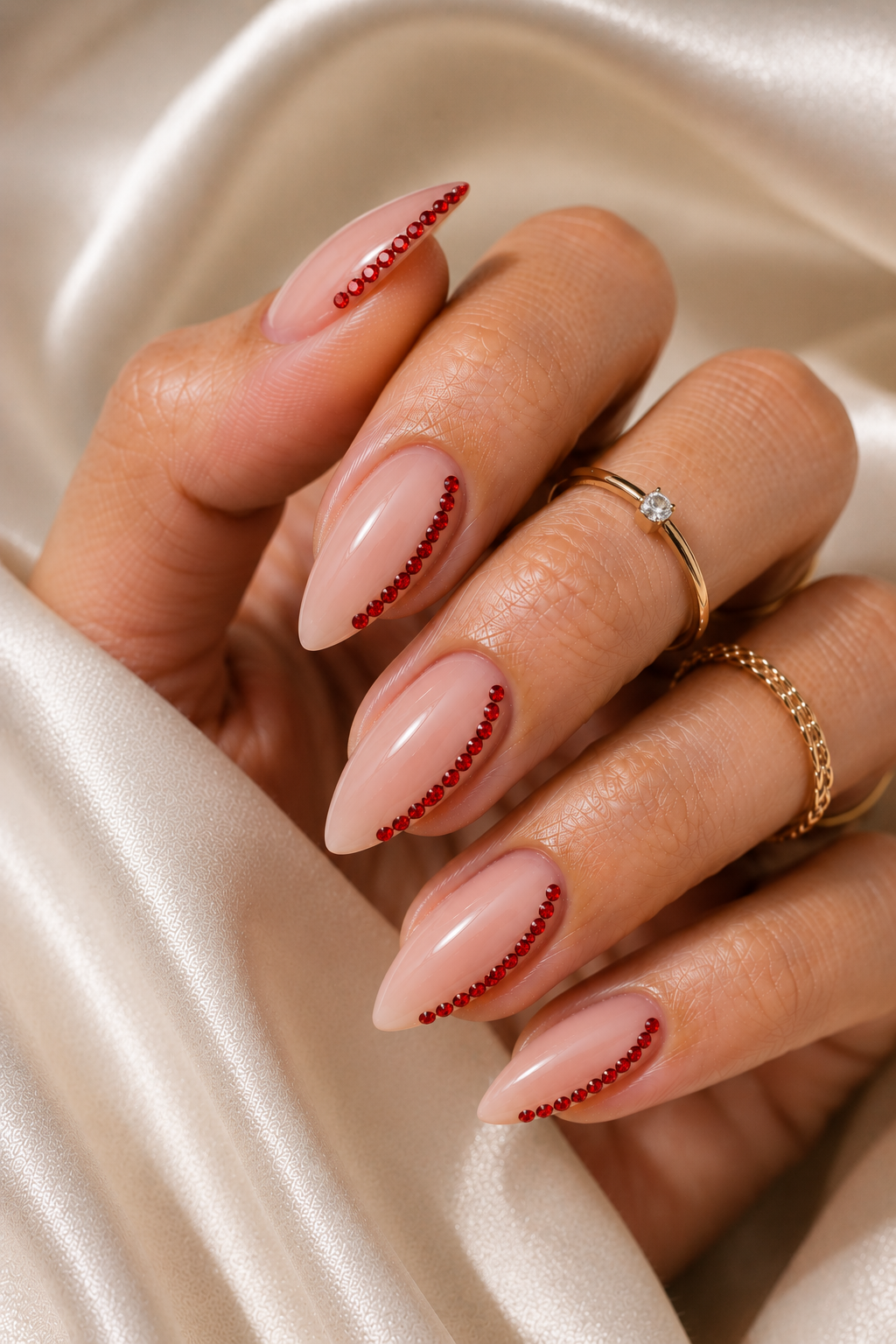 Short stiletto nails in glossy red with a single row of tiny clear rhinestones running along one side edge from mid-nail toward the tip.