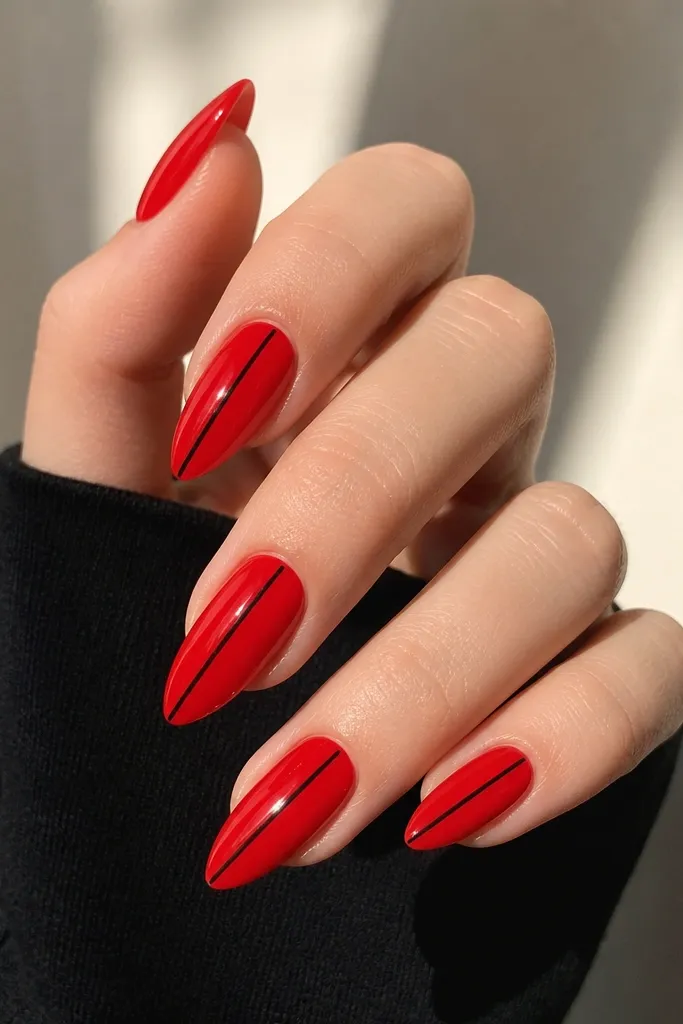 Short stiletto nails in true glossy red with one ultra-thin black line running down the center on each nail.