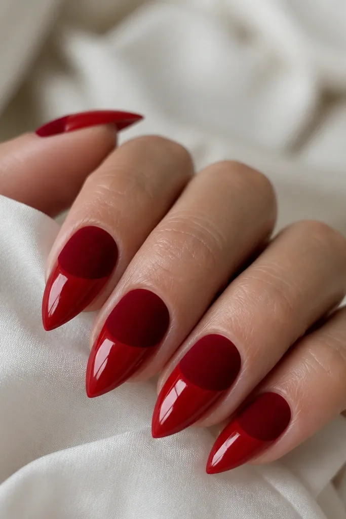 Short stiletto nails with the top half in red velvet matte and the bottom half in glossy red; the tip edge looks glossy and sealed.