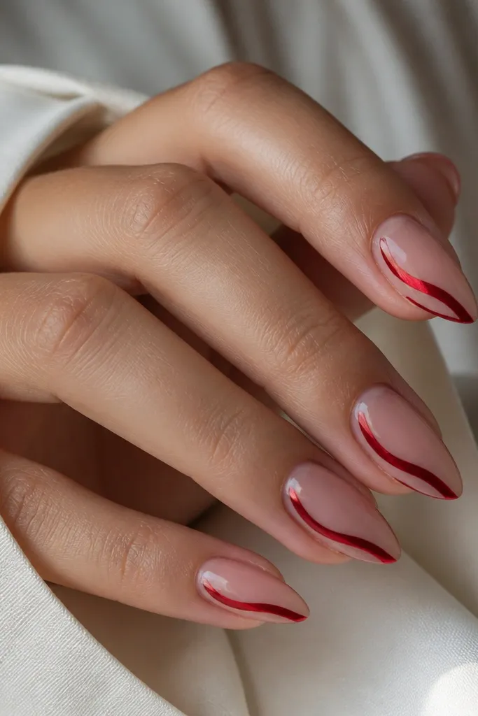 Short stiletto nails with a nude base; a red chrome swirl runs along one sidewall from mid-nail toward the tip; glossy finish.