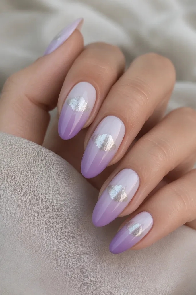 Almond nails with a lilac ombre that fades from almost white lilac at the cuticle to richer lavender at the tips. A silver chrome cloud sits on the top third with a hazy, feathered edge.