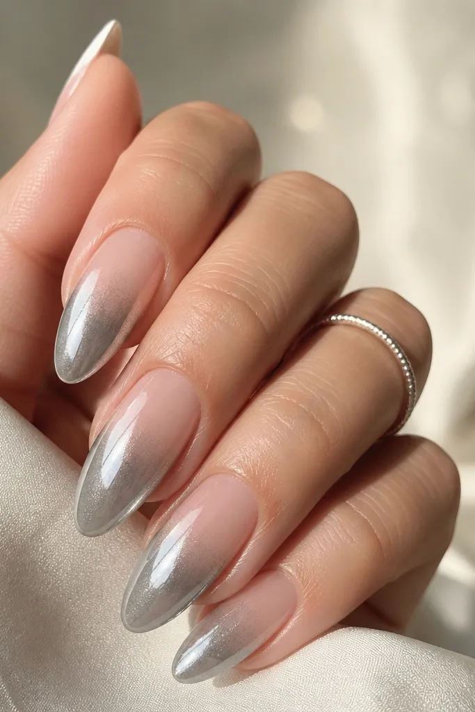 Long almond nails with a clear jelly base that fades from translucent at cuticle to pale gray at the tips. Silver chrome is layered from the top down, creating a true chrome gradient rather than a solid strip.