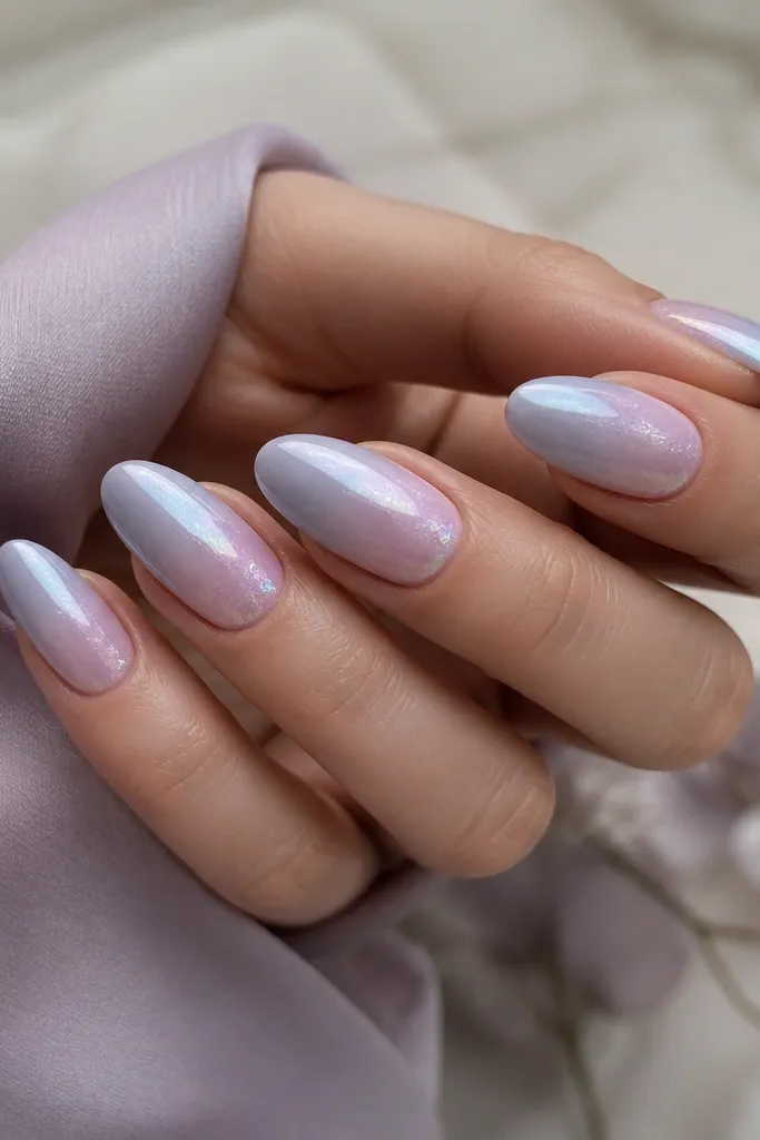 Almond nails with a lavender-grey ombre fading from light lilac at cuticle to cool grey-lavender at tips. Iridescent chrome is dusted lightly across the top third like a fog.