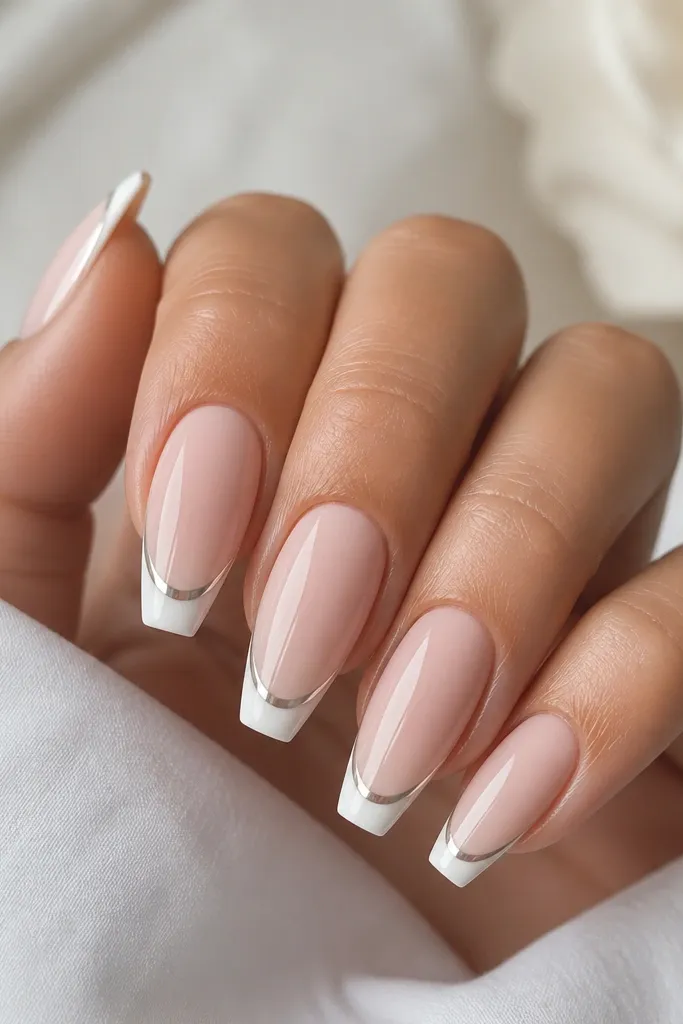 Coffin nails with sheer nude base; thin white French tips; a narrow silver chrome strip runs exactly along the smile line; glossy top coat.