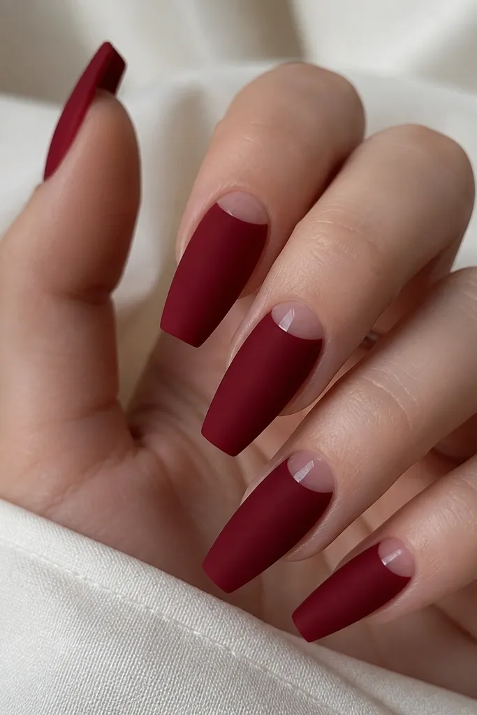 Short coffin nails painted deep red velvet matte; each nail has a glossy clear half-moon near the cuticle area.