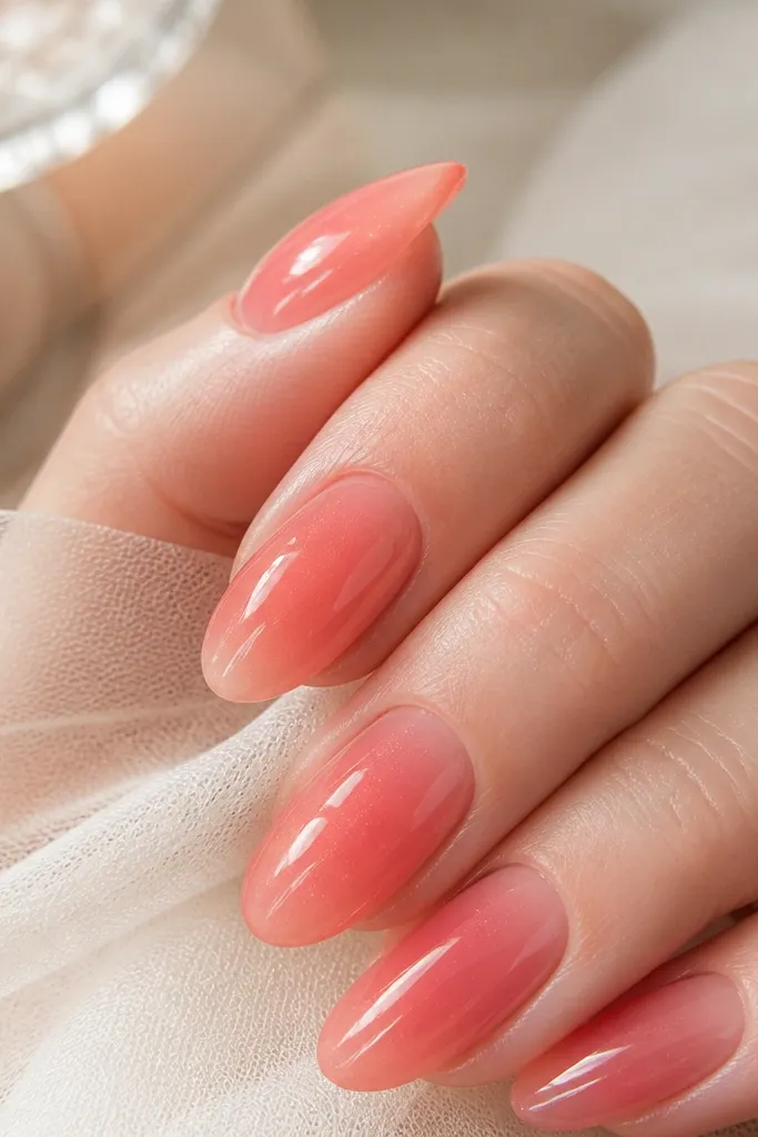 Glossy coffin nails in a jelly pink that shows a slight depth; tiny shimmer suspended inside the color.