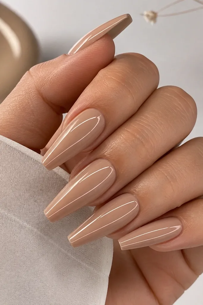 Coffin nails in warm nude with thin blush line art near the center ridge; glossy and clean.