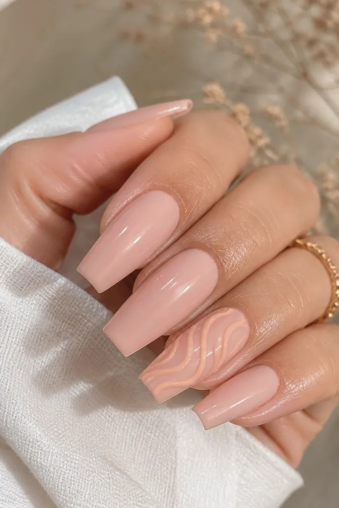 Glossy blush coffin nails with one accent nail featuring a peach velvet swirl line that looks slightly raised; rest are plain.