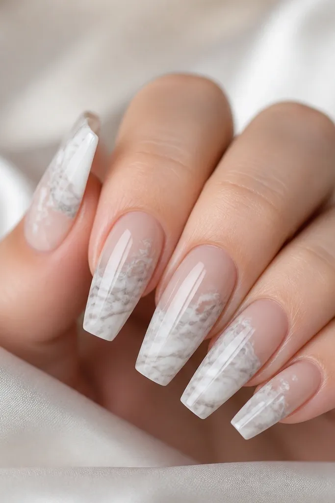 Coffin nails with nude base and marble swirls across the upper half of the nail, mostly white with gray undertones. Glossy finish.