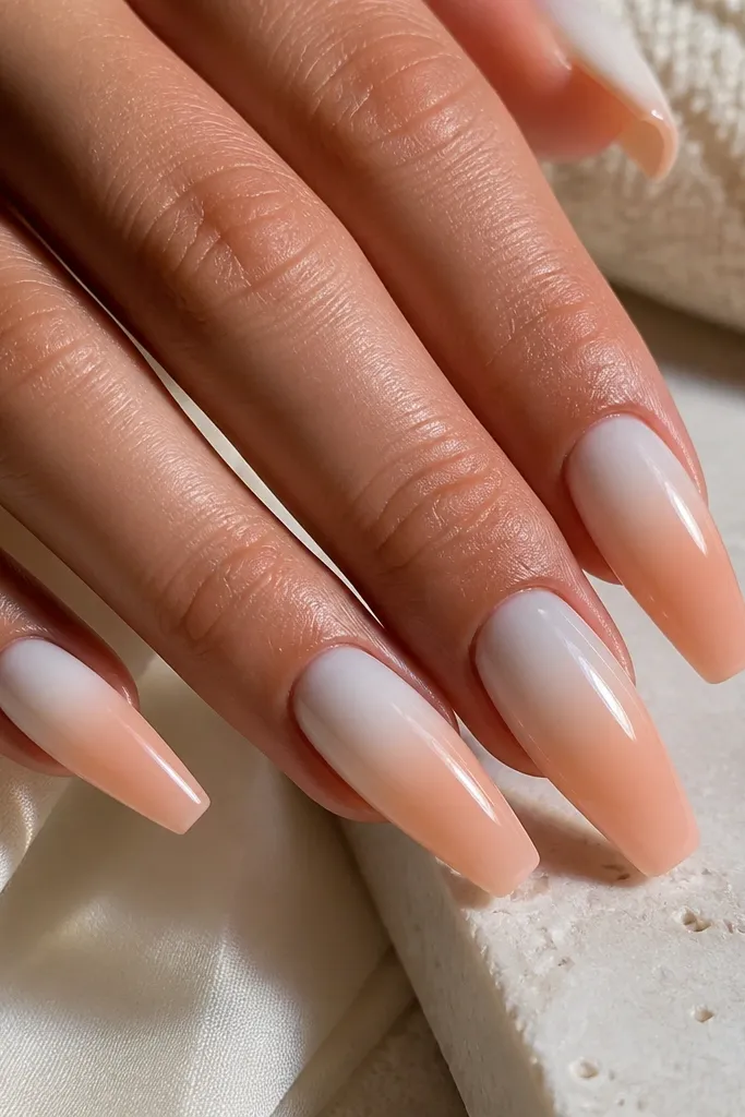 Coffin nails with a white milky base fading into peach from the middle down. The ombre is smooth with no harsh line, and the whole nail is glossy.