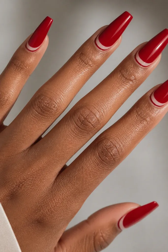 Red glossy coffin nails with a thin nude curved line that arcs near the cuticle like a smile.