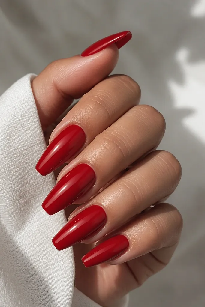 Red glossy coffin nails with a smooth, high-shine look and a faint lighter red "glaze" reflection near the center.