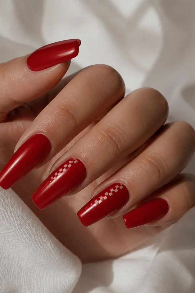 Red glossy coffin nails with tiny checker micro squares near the sidewall on one or two nails; the rest is solid red.