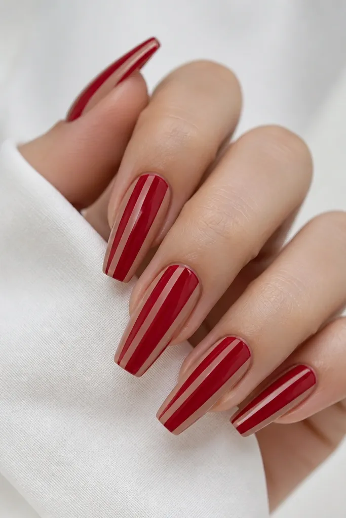 Red coffin nails with two thin nude stripes running vertically near each side of the nail, leaving the center solid red.