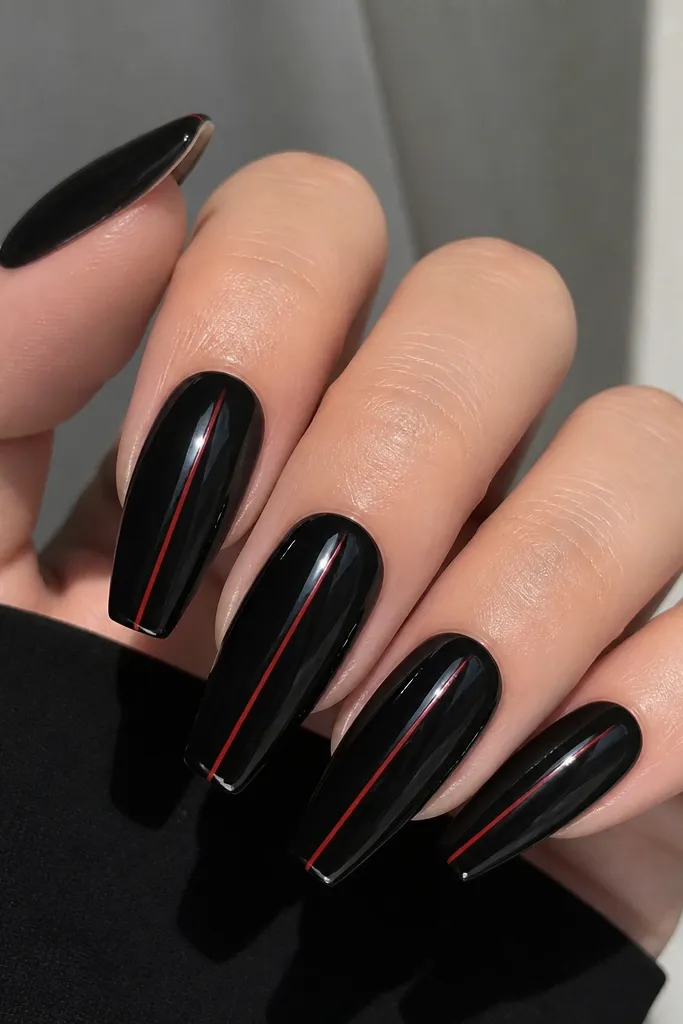 Coffin nails painted glossy black. A single ultra-thin red line runs down the center of each nail from near the middle to the tip, with no other decoration.