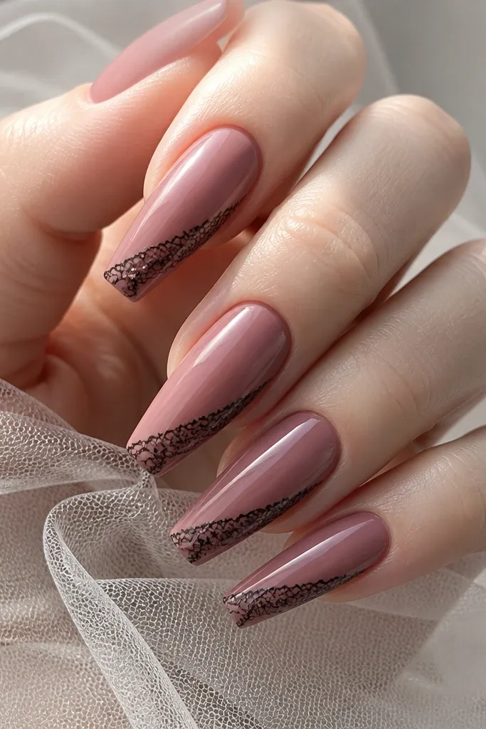 Coffin nails in smoked rose pink with glossy finish. Along the side near the tip, there's a thin black lace pattern like a ribbon trim, with delicate lines and tiny loops.