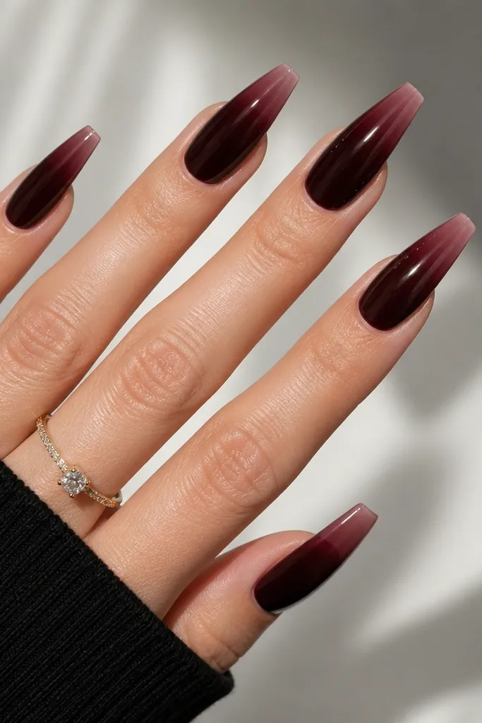 Coffin nails in black cherry red with glossy finish. The tips have a sheer pink overlay that fades upward, creating a smoky ombré effect.