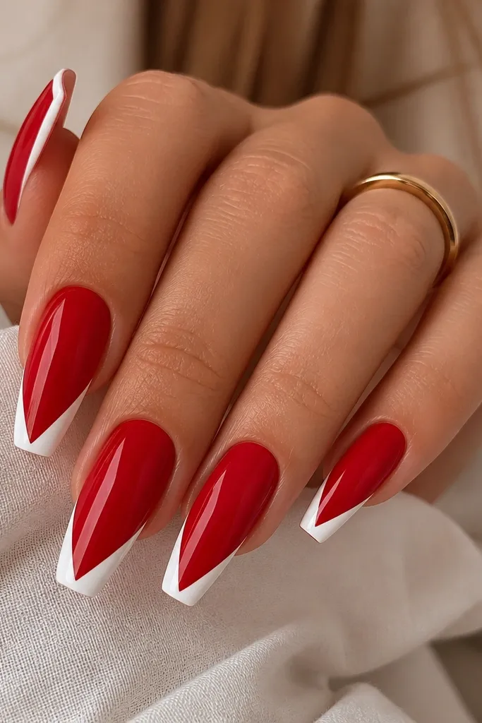 Coffin nails with glossy classic red base. Each nail has a white V-shaped French tip that meets at the center of the free edge. The V lines are crisp and symmetrical.
