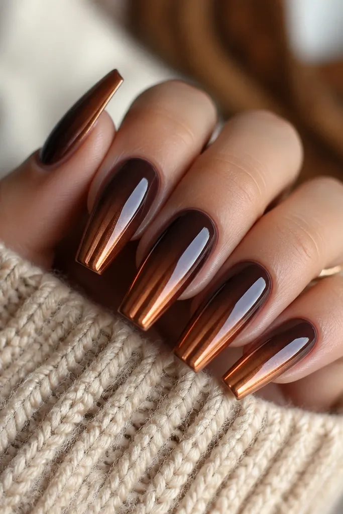 Medium coffin nails with a chocolate brown ombre fading into copper chrome tips. The copper reflects warm orange highlights and the gradient looks smooth with a glossy topcoat.