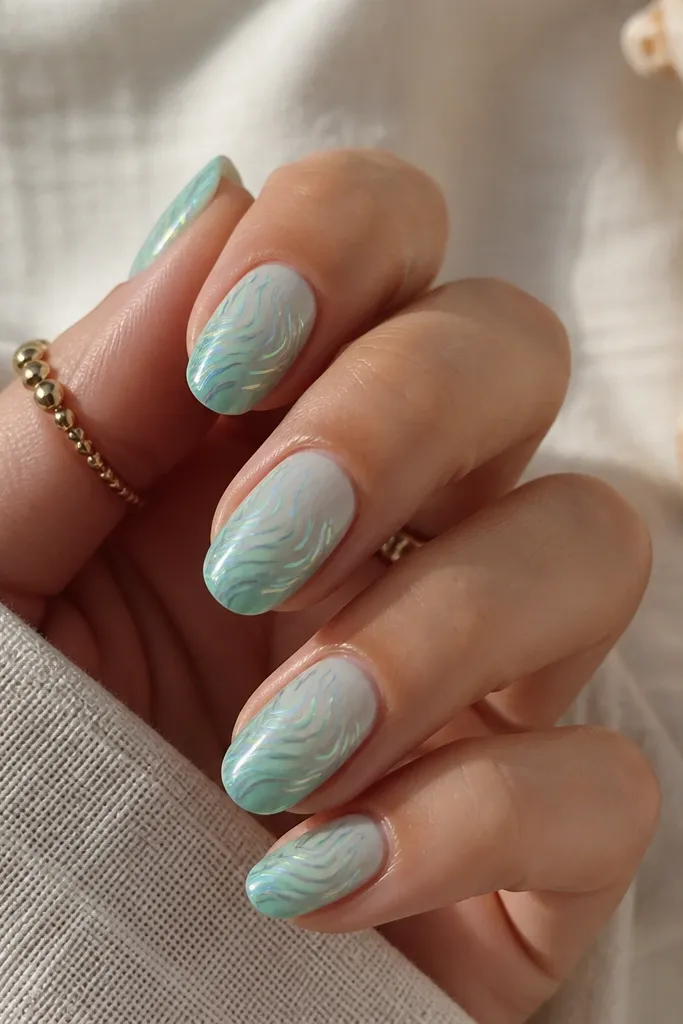 Medium oval nails fading from sheer mint at the cuticle to deeper seafoam at the tips. Holographic wave lines run across the nail, creating a moving light effect over the chrome.