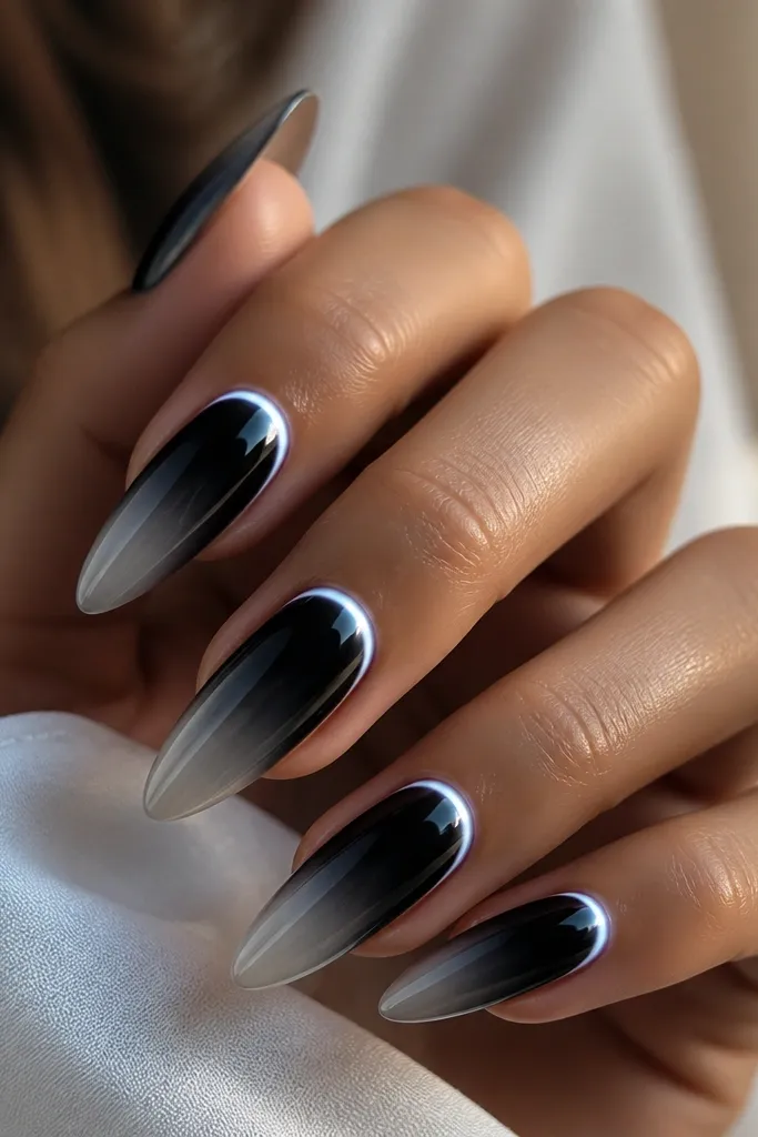 Long almond nails fading from onyx black at the base to smoky grey near the tip. White chrome is mirror, and a cold white halo ring glows around the cuticle.