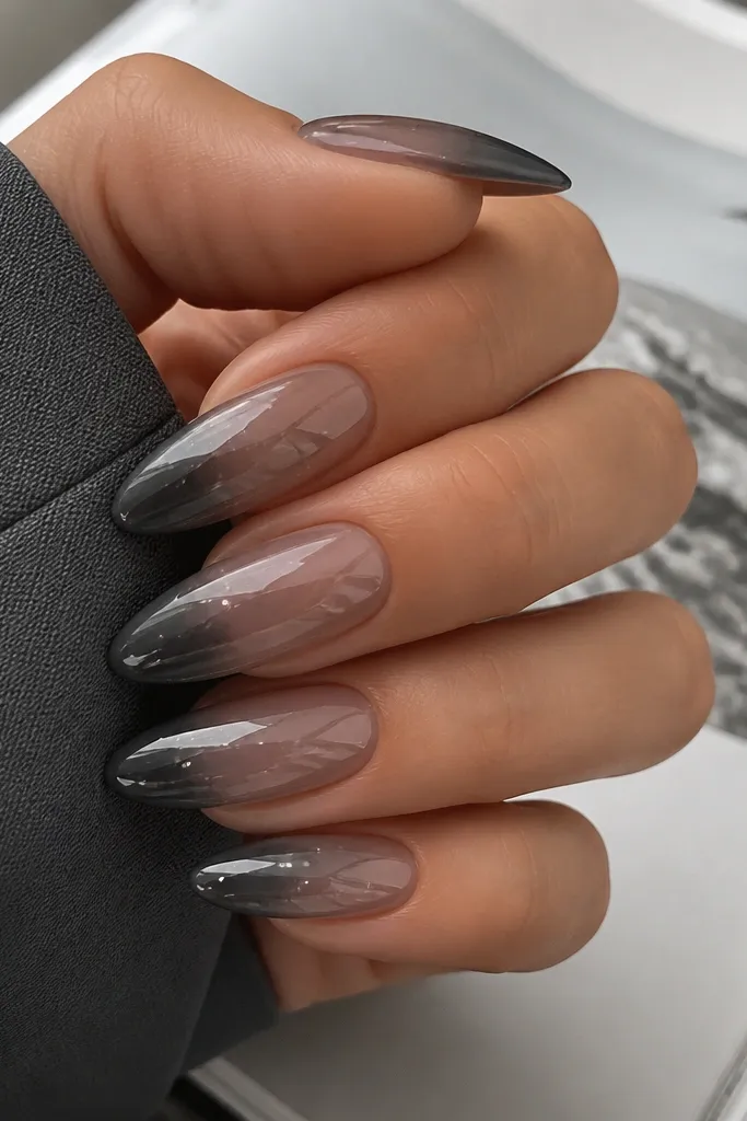 Long almond nails fading from sheer smoke grey to deeper graphite at the tip. Graphite chrome is mirror, and cool white flash dots sit in a scattered pattern near the center.