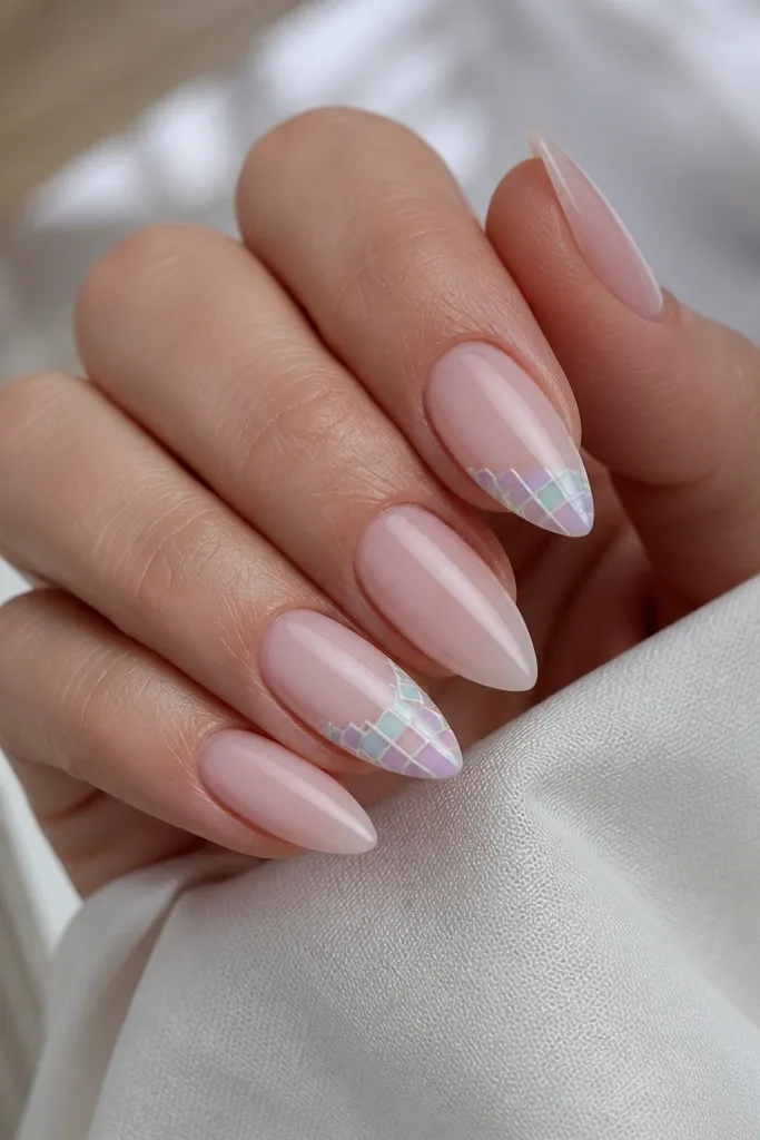 Short stiletto nails with a pale pink base. Two nails have a tiny pastel checker pattern in mint, lavender, and baby blue near the tip, outlined with thin white lines.