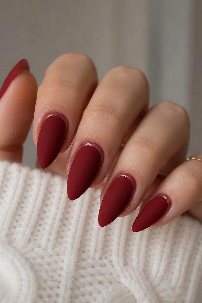 Short stiletto nails in deep red matte. A thin glossy clear border outlines the cuticle area like a crescent, making the matte red look extra plush.