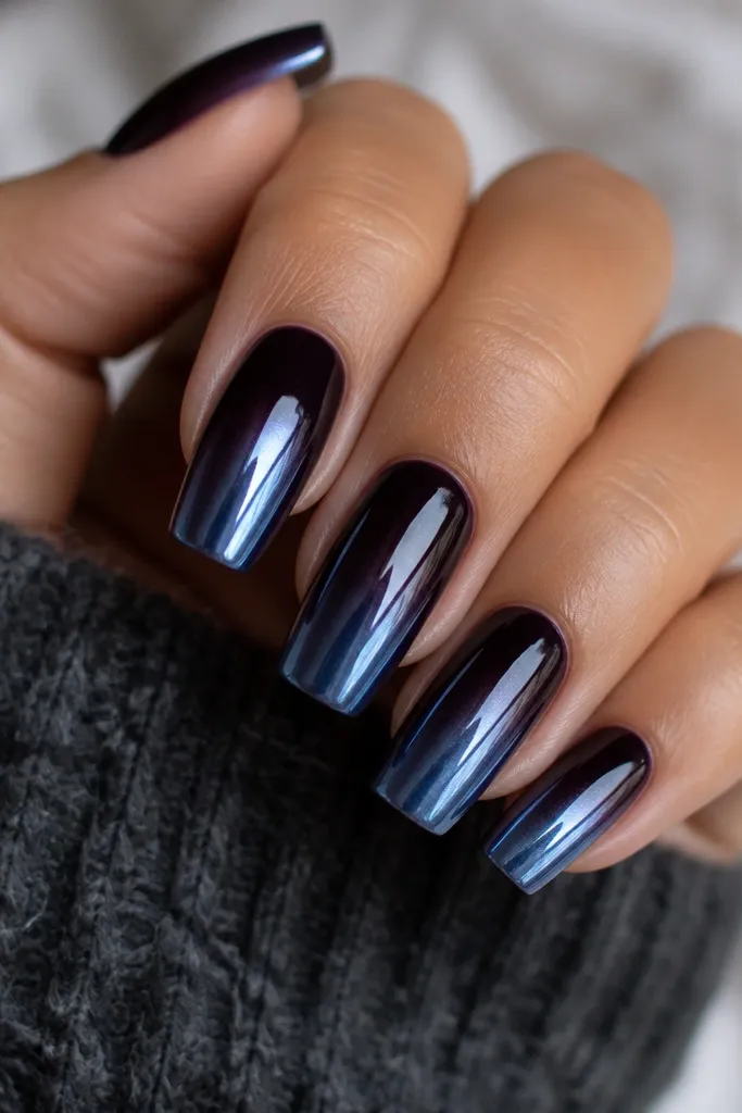 Long squoval nails with a black plum base that fades into steel-blue chrome at the tips. The chrome reflects blue-gray mirror highlights, while the plum stays deep and glossy.
