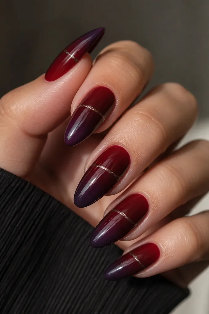 Long almond removable nails with a black cherry ombre that fades into a dark plum at the tip. A thin graphite chrome thread runs diagonally across the upper third, like a metallic seam.