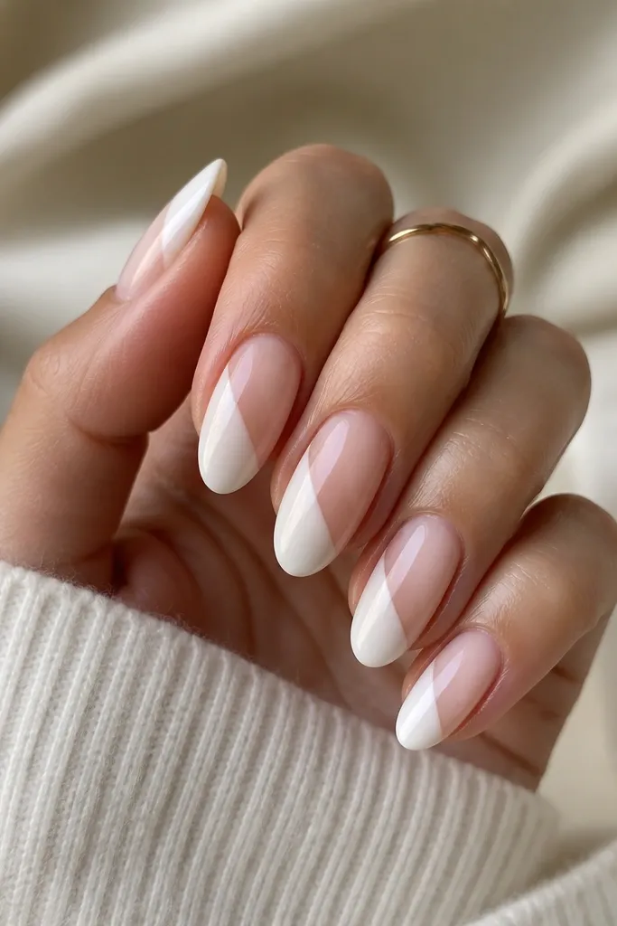 Short nails with a nude base; a diagonal milky white stripe runs from lower left to upper right on each nail, leaving a clear negative space triangle.