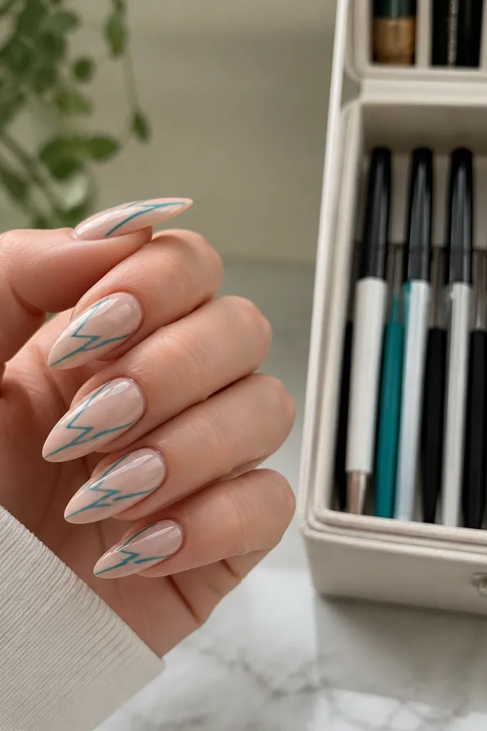 Short stiletto nails with nude glossy base. Thin teal lightning bolt lines run diagonally across each nail. A storage organizer shows gel liner pens in a dedicated slot.