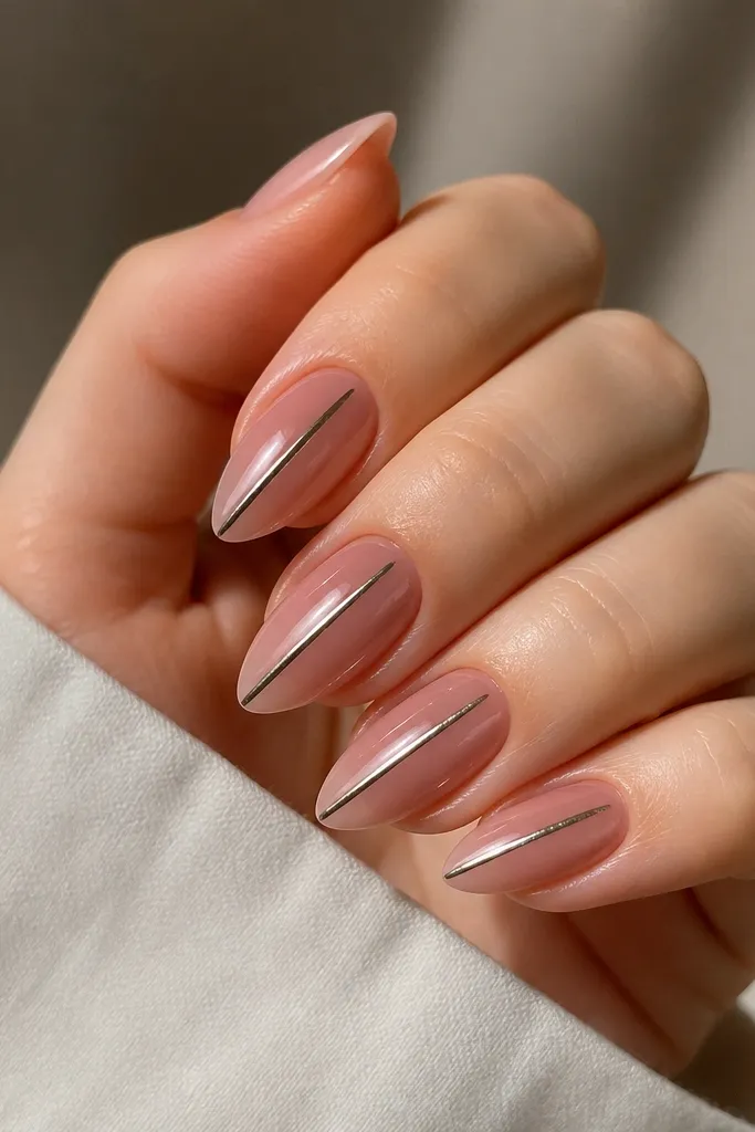 Short stiletto nails with nude-pink chrome shine. A thin black cat-eye line runs vertically down the center on each nail, crisp and reflective.