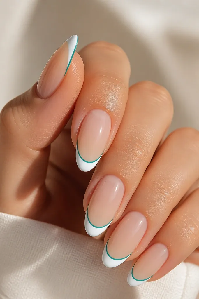 Short nails with nude base. White French tips have a thin teal outline along the outer edge of the white. Glossy finish, crisp teal line.