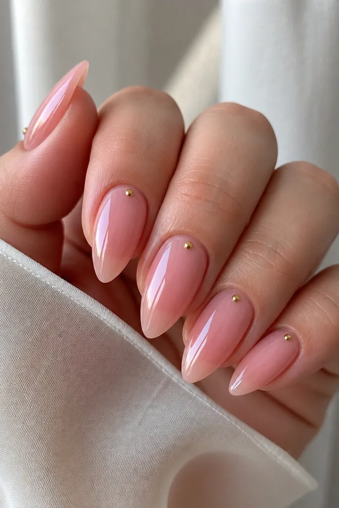 Short acrylic stiletto nails with a clear-pink jelly base; one tiny gold dot sits close to the cuticle on each nail, and everything is glossy.