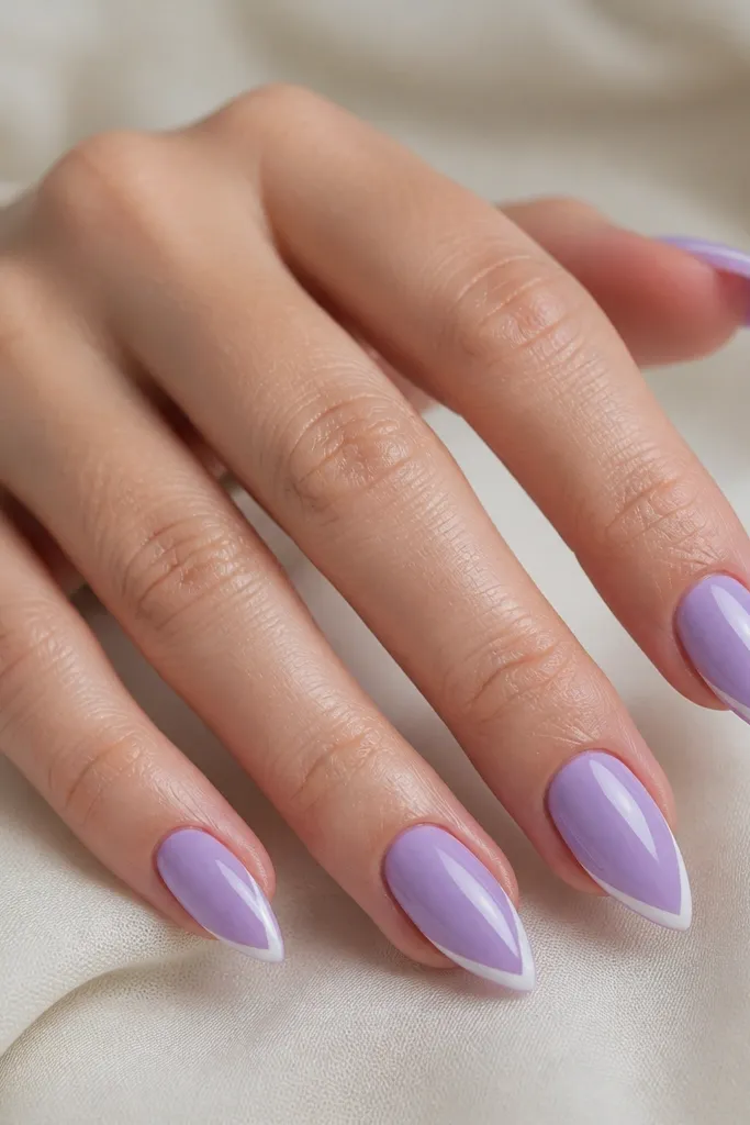 Short stiletto nails in glossy lavender; each tip has a thin white V shape pointing upward in the center; clean and symmetrical.