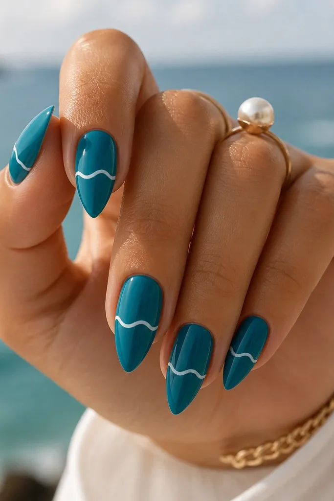 Short stiletto nails in glossy ocean teal; one thin white wave line runs horizontally across each nail near the middle; the rest is solid teal.