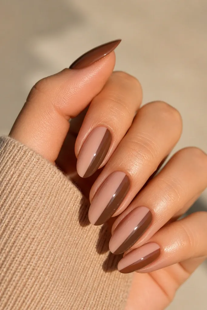 Short square nails with a nude base. On each nail, one half of the nail is painted mocha brown from the sidewall toward the center, like a clean half-panel. The line is straight and vertical.