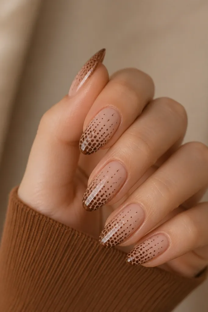 Short nails with nude base. At the tips, there's a gradient of espresso dots getting larger and denser at the very edge, fading smaller toward the center. Glossy top.