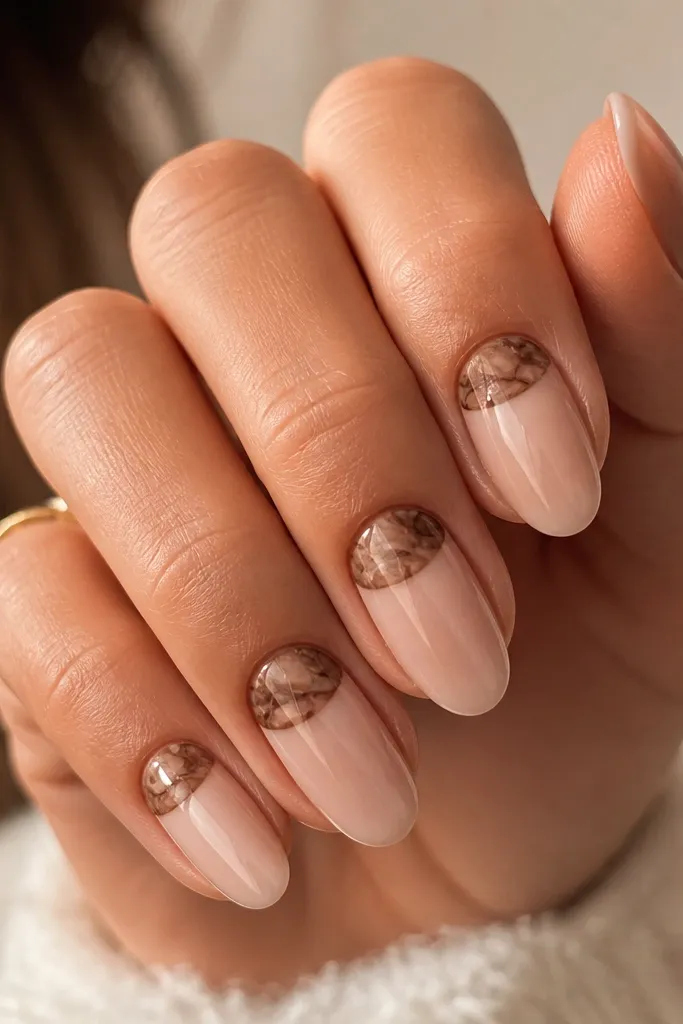 Short nails with a deep mocha base. The cuticle area has a lighter marble-like curved panel in taupe and milky brown, like a reverse French. The rest of the nail is solid mocha. Glossy top.