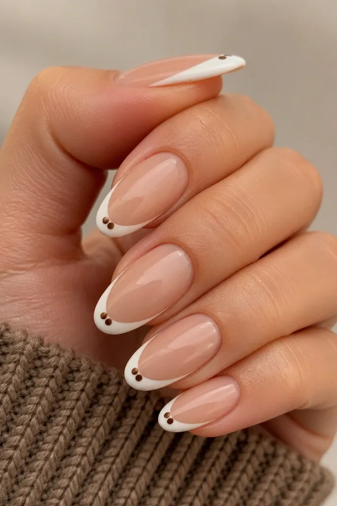 Nude nails with a thin French tip. Each nail has exactly two brown polka dots - one on each side of the center - sitting right along the smile curve of the French line.